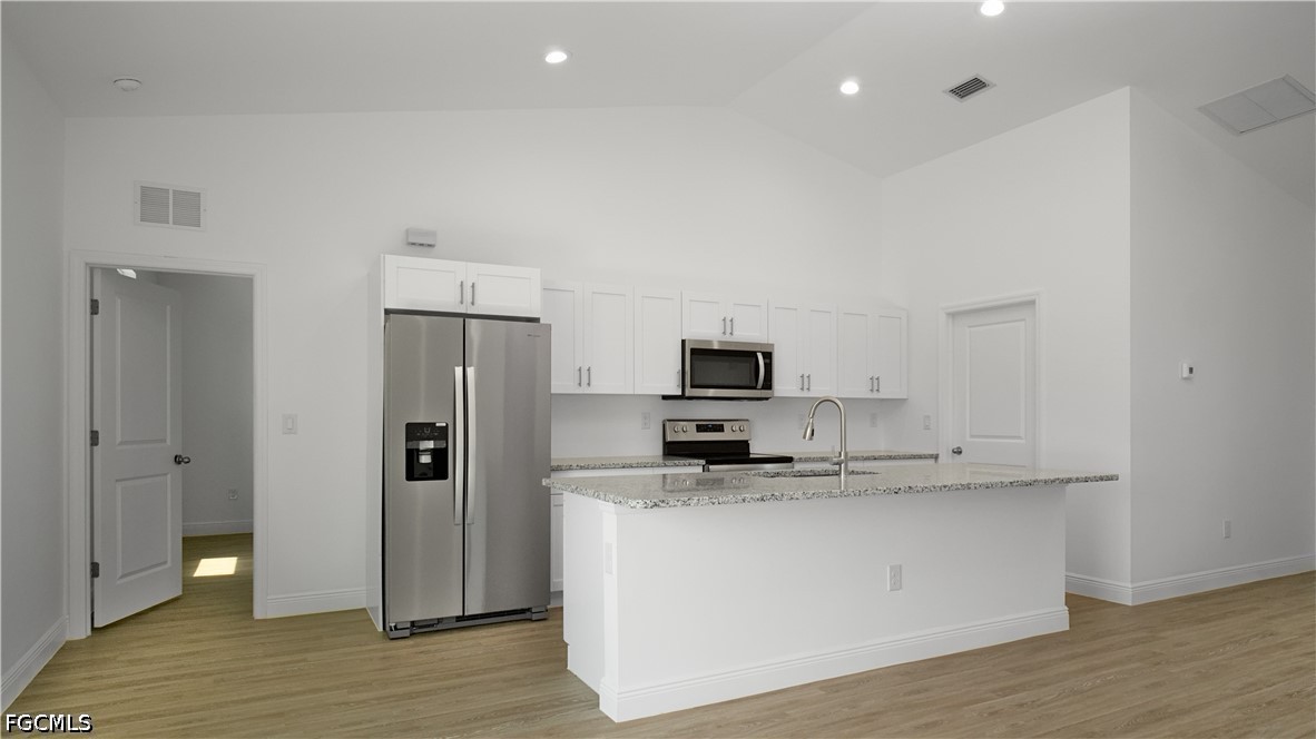 5021 Myrtlewood Road LaBelle, FL 33935 - Photo 8 of 10 a large kitchen with stainless steel appliances a refrigerator a stove a sink and a stove with wooden floor