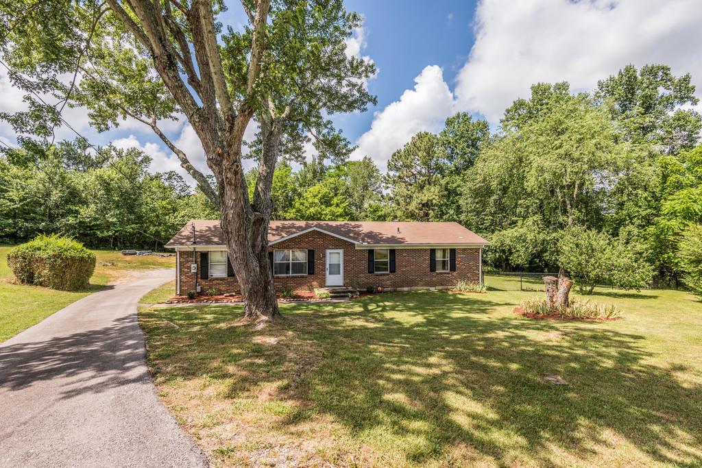 a front view of a house with a yard and large trees
