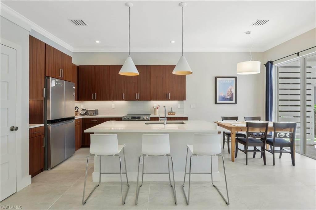 5717 Lago Villaggio Way Naples, FL 34104 - Photo 14 of 35 a kitchen with stainless steel appliances kitchen island granite countertop a dining table and chairs