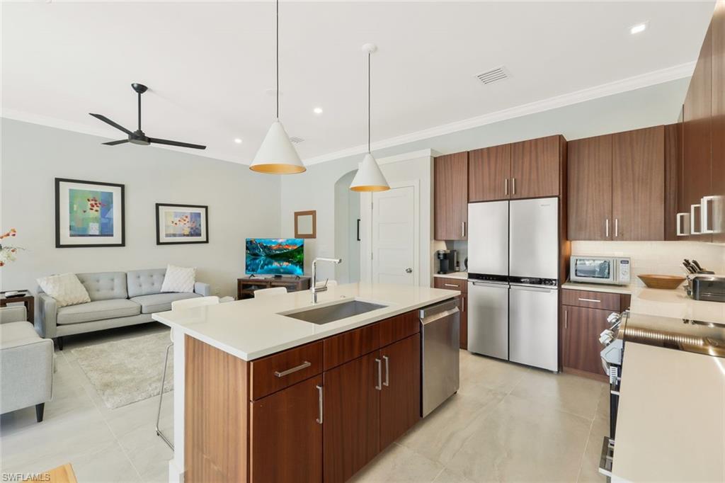 5717 Lago Villaggio Way Naples, FL 34104 - Photo 15 of 35 a kitchen with a sink a stove a refrigerator and white cabinets