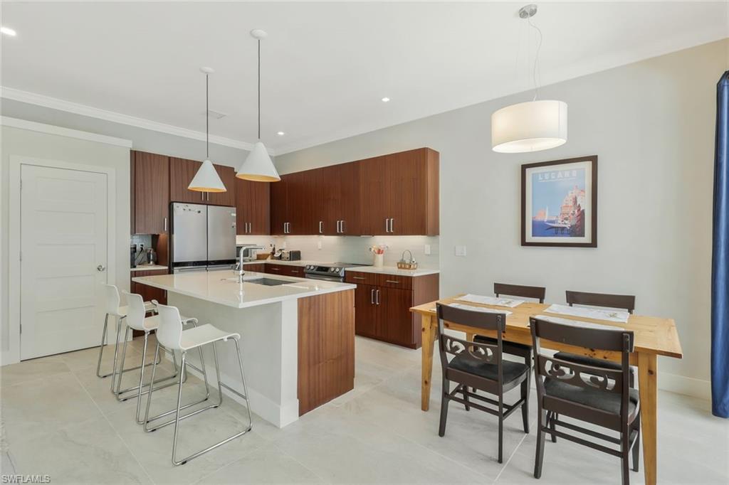 5717 Lago Villaggio Way Naples, FL 34104 - Photo 19 of 35 a kitchen with a dining table chairs and a refrigerator
