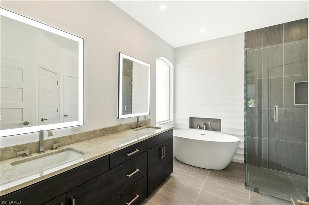 5717 Lago Villaggio Way Naples, FL 34104 - Photo 23 of 35 a bathroom with a double vanity sink mirror and bathtub