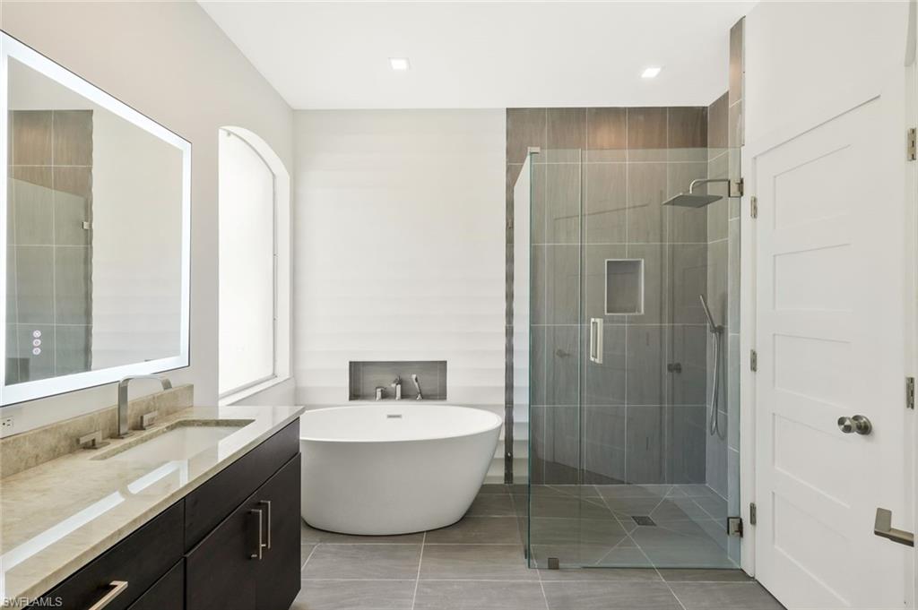 5717 Lago Villaggio Way Naples, FL 34104 - Photo 24 of 35 a bathroom with a granite countertop sink toilet and shower