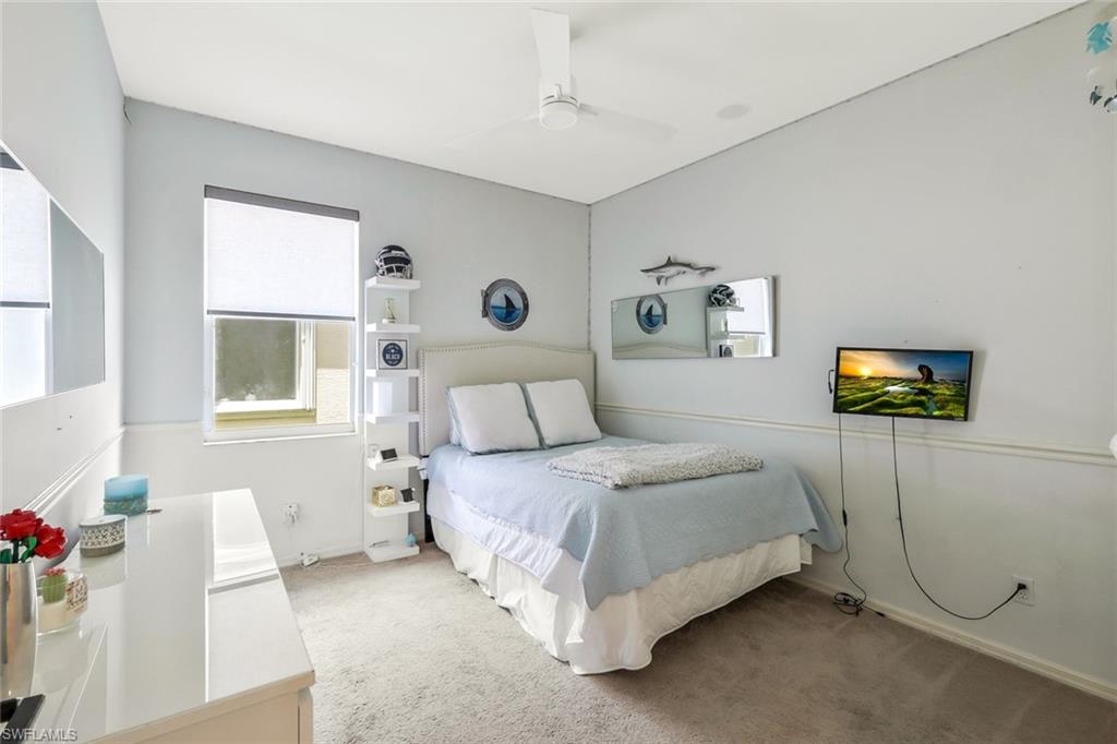 5717 Lago Villaggio Way Naples, FL 34104 - Photo 25 of 35 a spacious bedroom with a bed a couch and a window