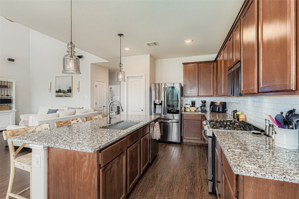 1075 Cherrystone Loop Buda, TX 78610 - Photo 11 of 28 a kitchen with stainless steel appliances granite countertop a sink stove and refrigerator