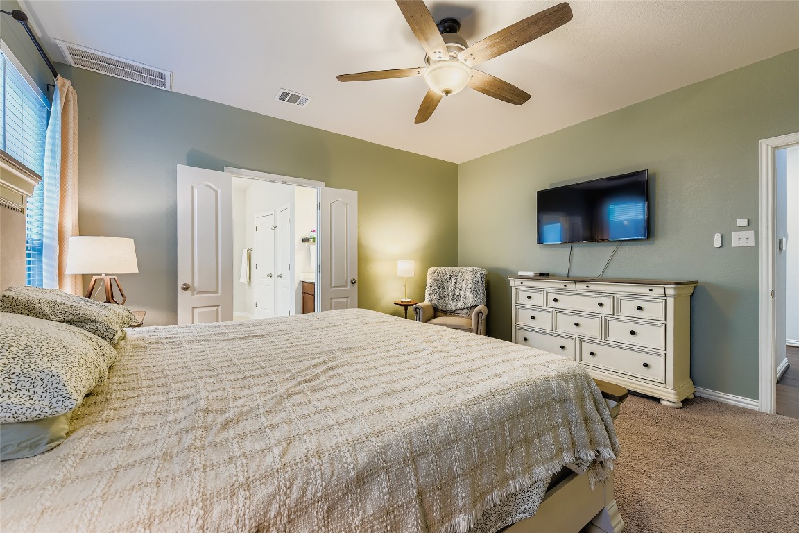 1075 Cherrystone Loop Buda, TX 78610 - Photo 14 of 28 a bedroom with a bed a flat screen tv and a chandelier