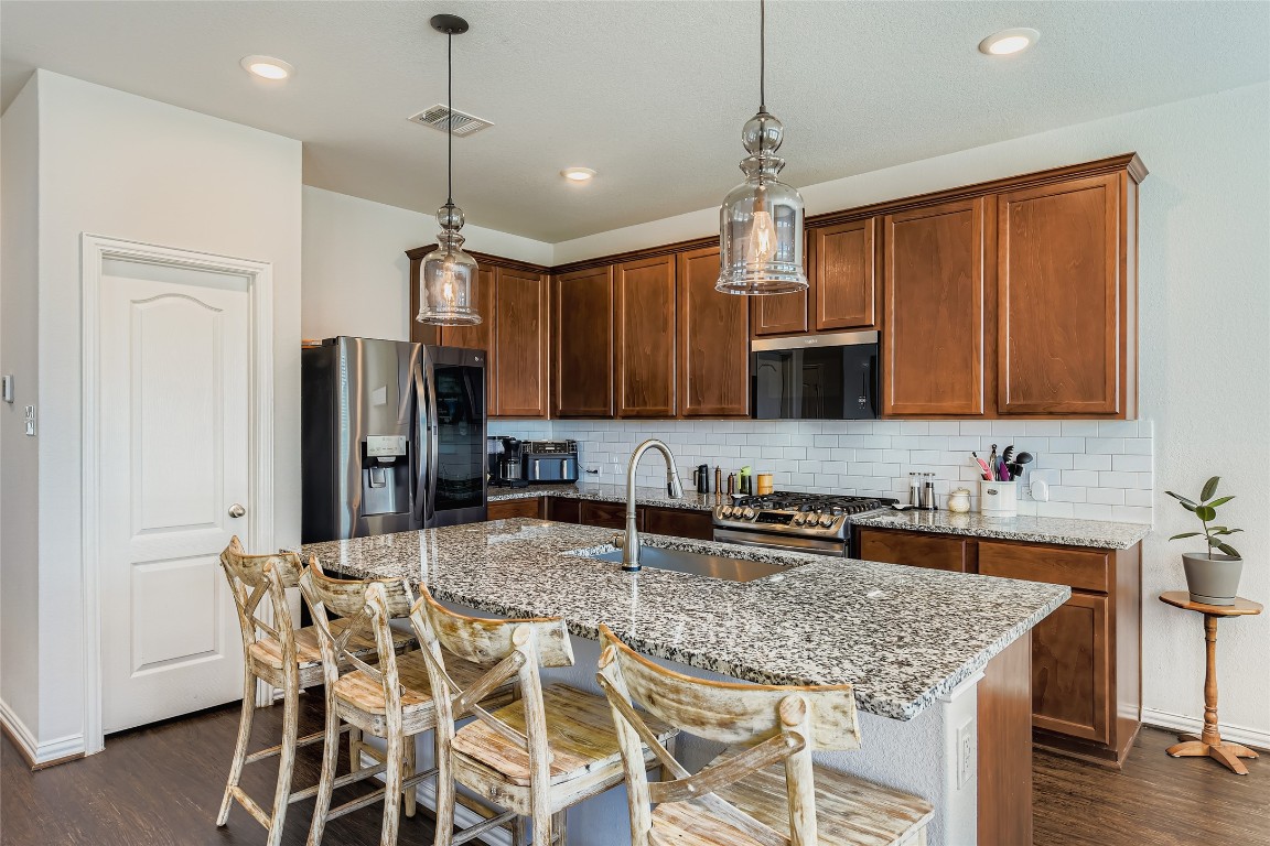 1075 Cherrystone Loop Buda, TX 78610 - Photo 9 of 28 a kitchen with stainless steel appliances granite countertop a sink refrigerator and microwave