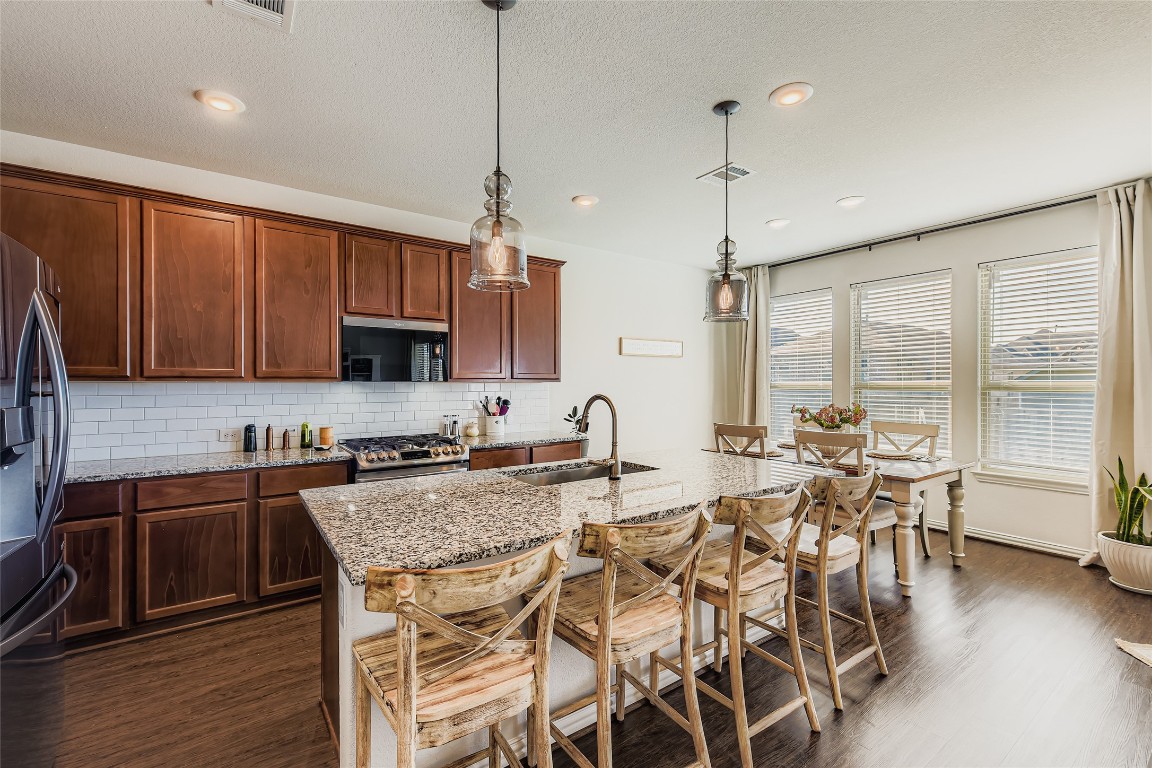1075 Cherrystone Loop Buda, TX 78610 - Photo 10 of 28 a kitchen with granite countertop a table chairs stove and cabinets