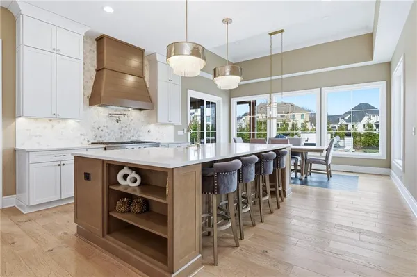 a kitchen with stainless steel appliances granite countertop a stove a refrigerator a sink a dining table and chairs with wooden floor