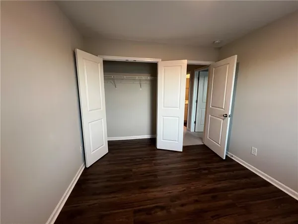 a view of an empty room with wooden floor and closet