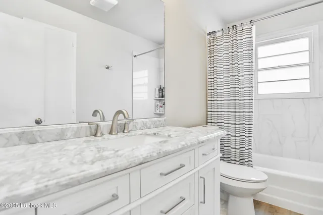 a bathroom with a granite countertop sink a toilet and a bathtub