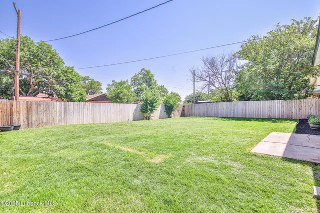 a view of yard with small play ground and wooden fence