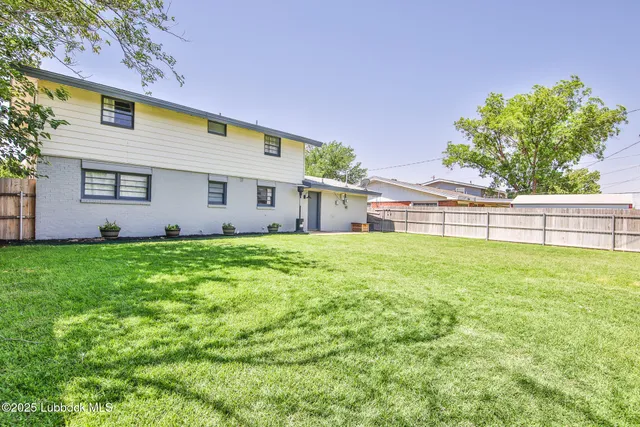 a view of house with backyard and a tree