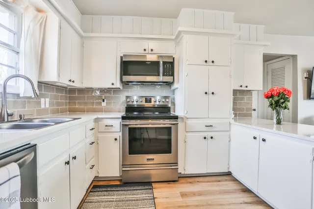 a kitchen with white cabinets stainless steel appliances and sink