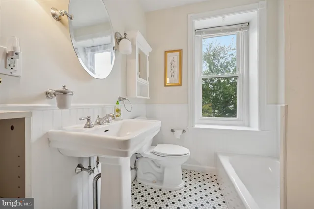 a bathroom with a sink a toilet a window and shower