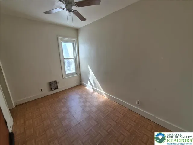 an empty room with a chandelier fan and windows