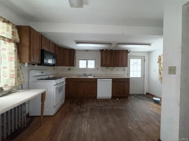 a kitchen with stainless steel appliances kitchen island granite countertop a sink dishwasher stove and microwave with wooden floor