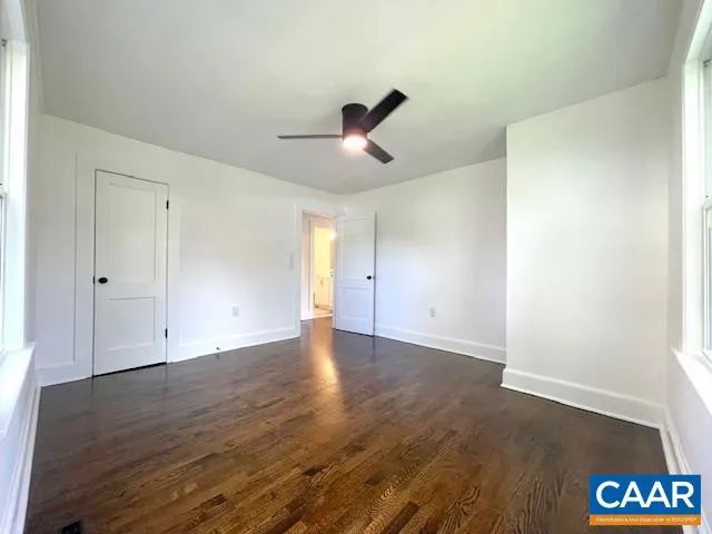 an empty room with wooden floor and ceiling fan