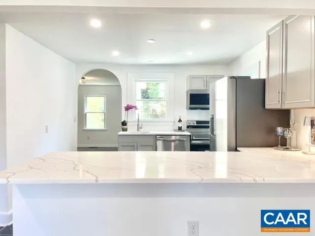 a view of a kitchen with kitchen island granite countertop a sink and refrigerator