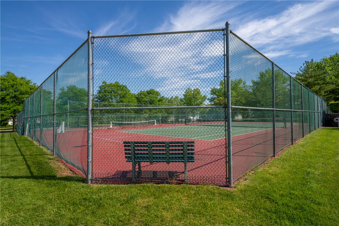 4236 Creek Road Allentown, PA 18104 - Photo 47 of 47 Lush green grass surrounds a fenced tennis court beneath clear blue skies.