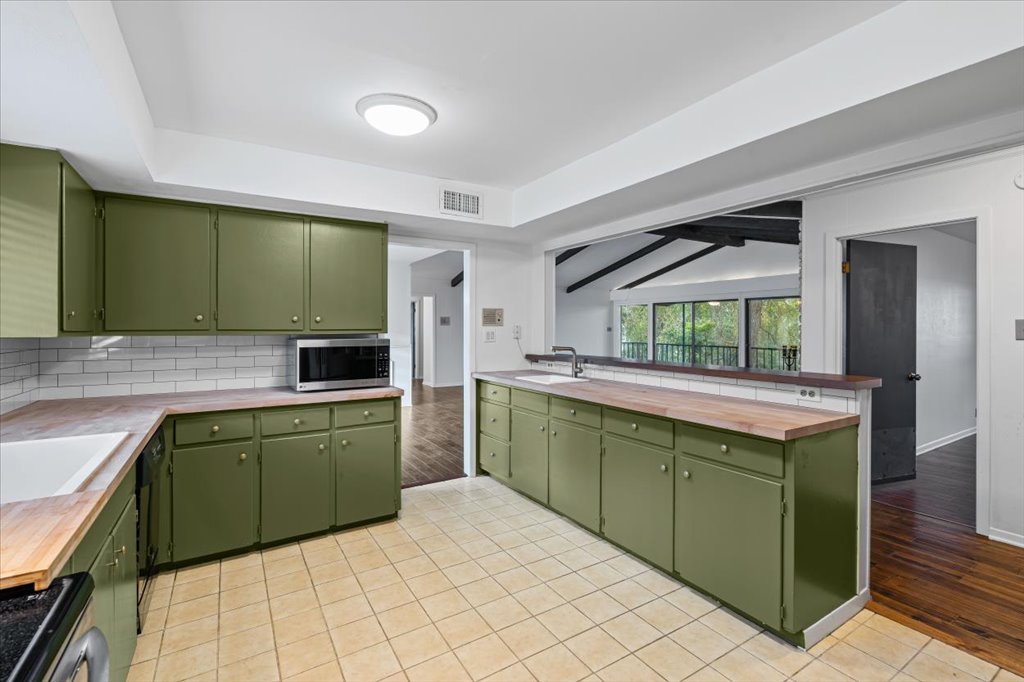 313 Comet Lakeway, TX 78734 - Photo 5 of 17 Kitchen with light tile floors, painted cabinets, decorative backsplash, range, and stainless steel microwave