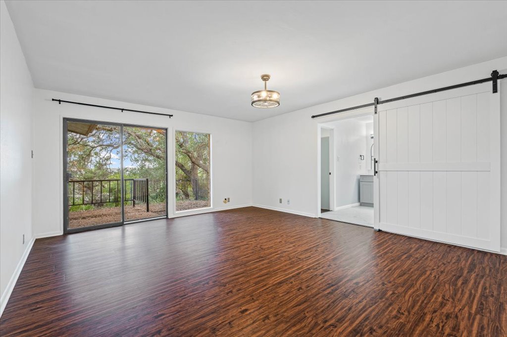 313 Comet Lakeway, TX 78734 - Photo 6 of 17 Primary bedroom with a barn door, wood-style floors, and a chandelier