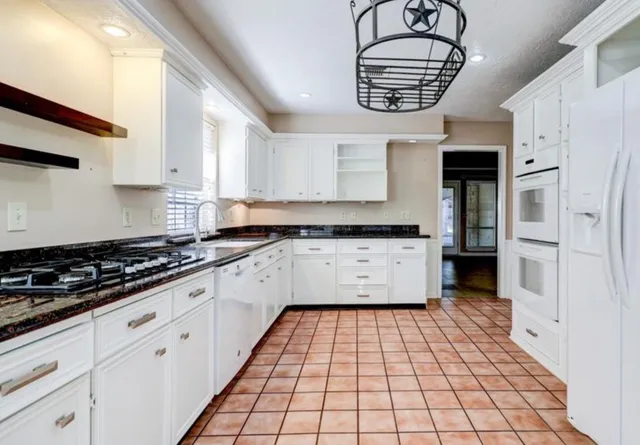 a kitchen with granite countertop a stove a sink and a refrigerator