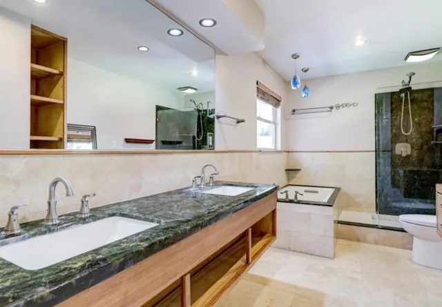 a bathroom with a granite countertop sink a large mirror and shower
