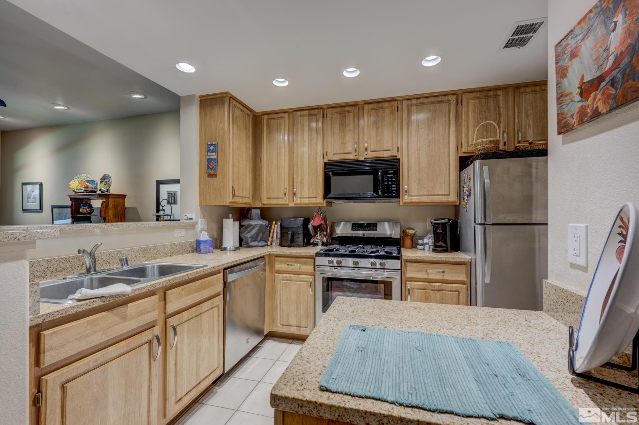 900 S Meadows, Unit 613 Reno, NV 89521 - Photo 12 of 40 a kitchen with stainless steel appliances a stove refrigerator sink and microwave