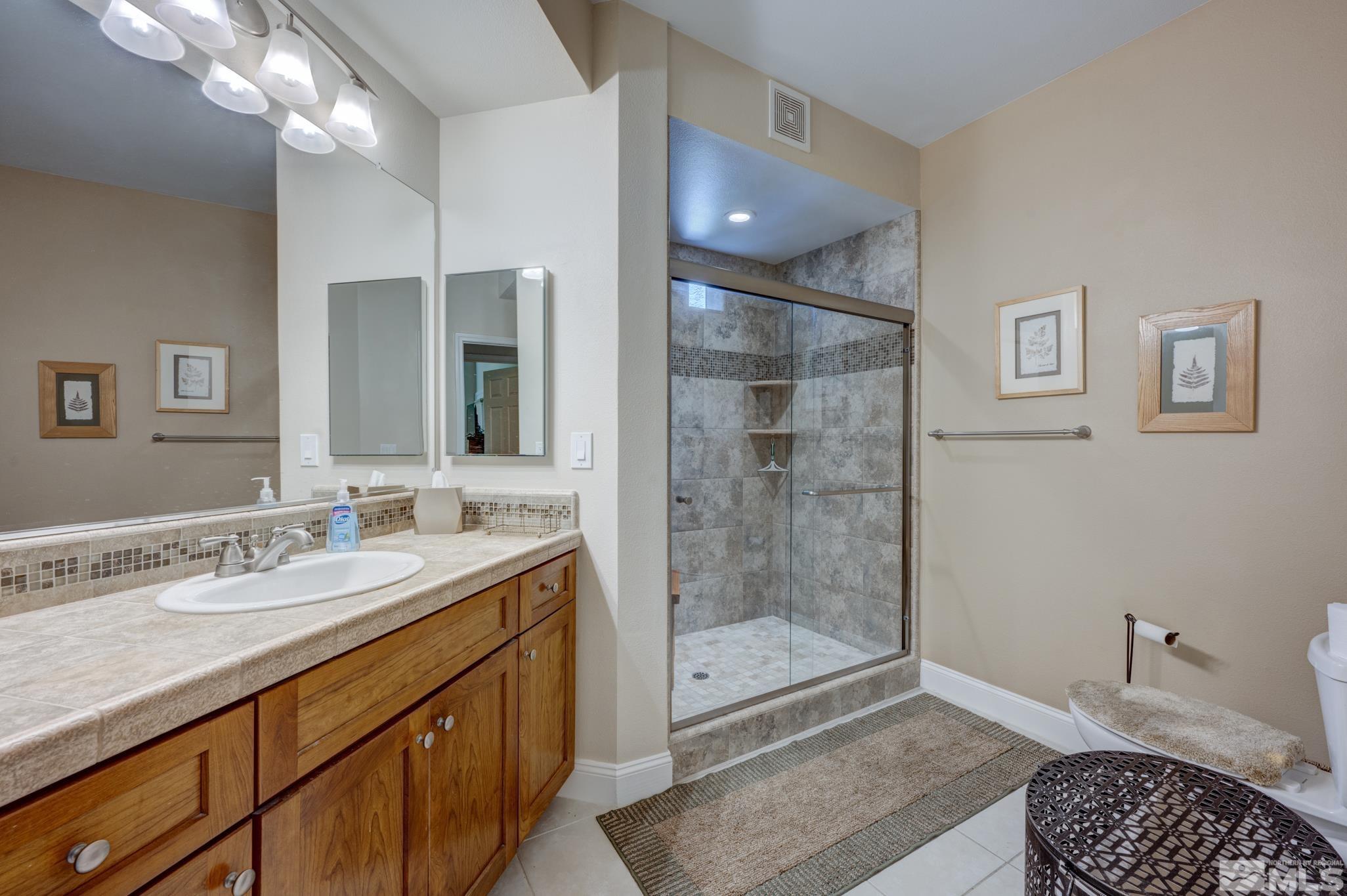 900 S Meadows, Unit 613 Reno, NV 89521 - Photo 3 of 40 a bathroom with a granite countertop sink a mirror and a shower