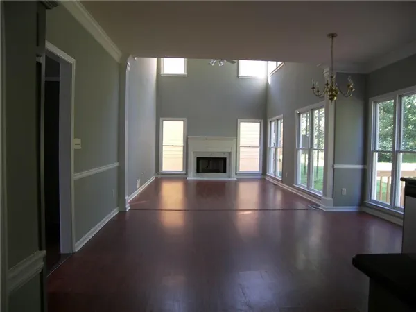 an empty room with floor to ceiling windows and fireplace