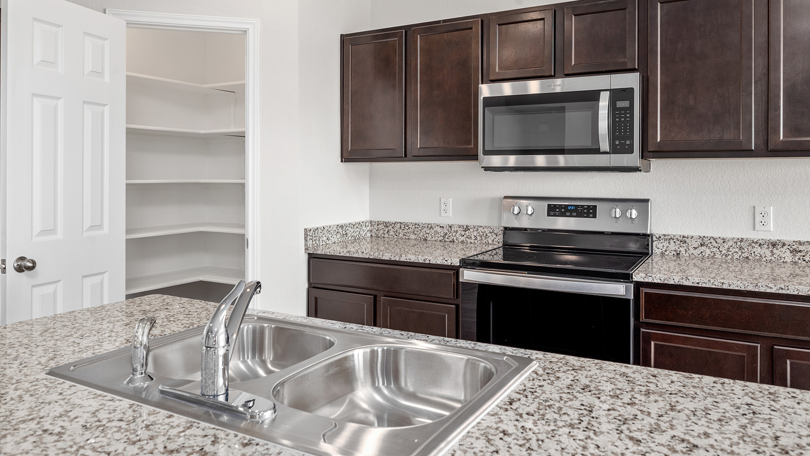 148 McNamara Court Jarrell, TX 76537 - Photo 4 of 22 Kitchen with stainless steel appliances, dark wood finish cabinetry, and light stone counters