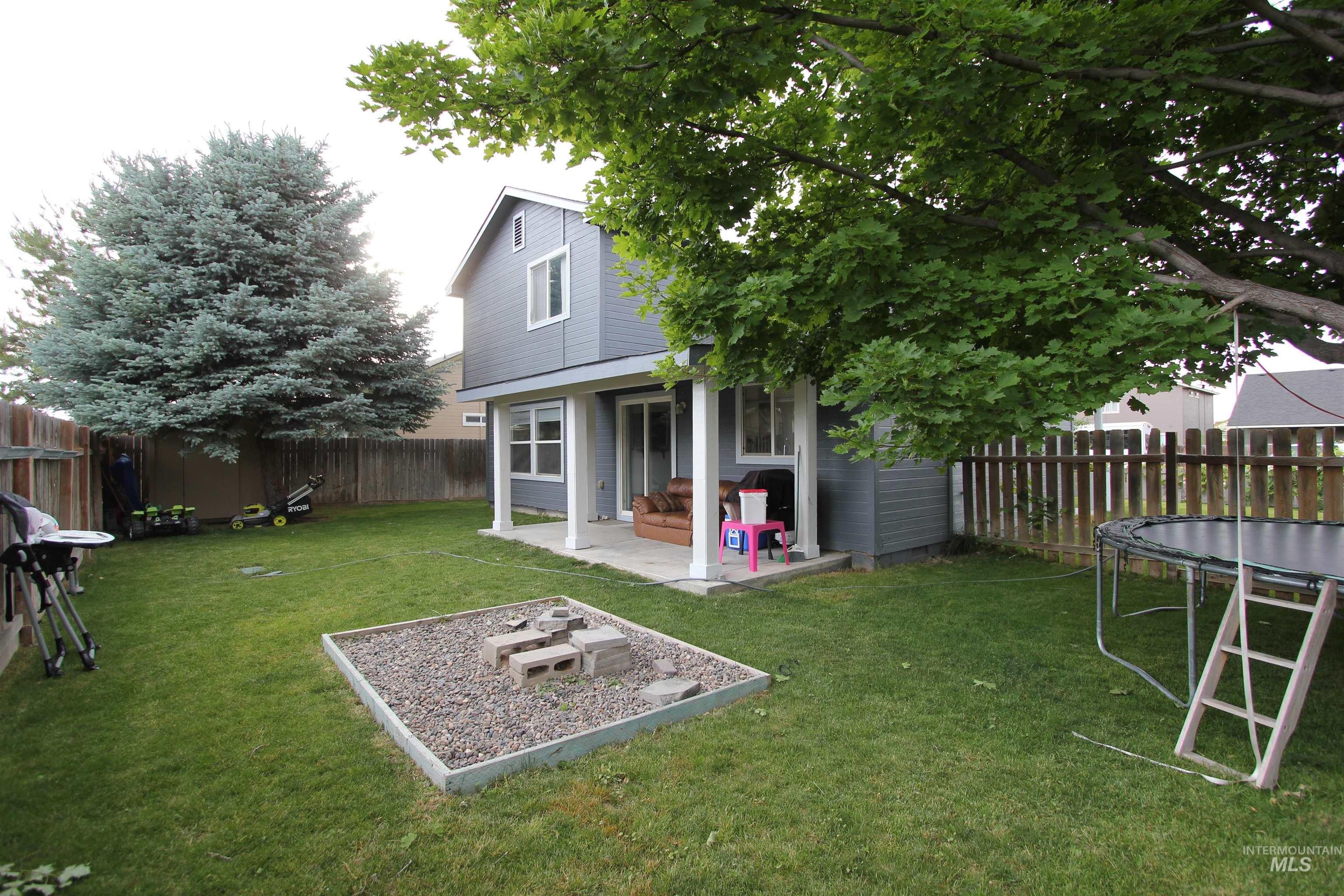4816 Kadie Street Caldwell, ID 83607 - Photo 23 of 23 Spacious backyard featuring a manicured lawn, a gravel fire pit area, and mature trees providing natural shade