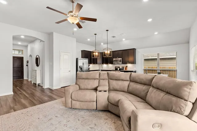 a kitchen with stainless steel appliances granite countertop a sink a stove top oven a dining table and chairs with wooden floor