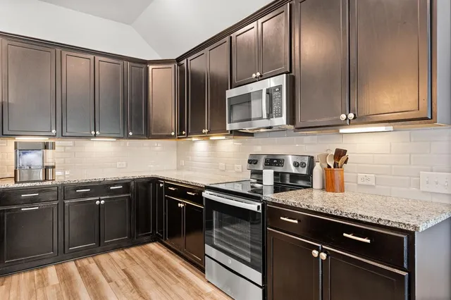 a large kitchen with kitchen island a stove a sink a oven and a dining table with wooden floor