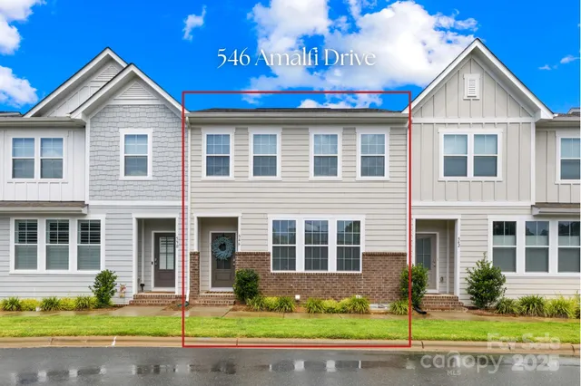 a front view of a house with a yard and potted plants
