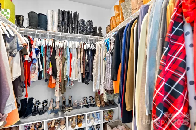 a view of walk in closet with clothes and shoes