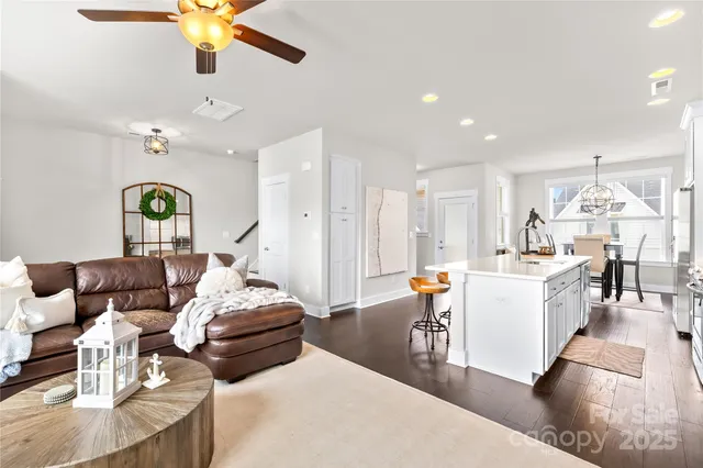 a living room with furniture kitchen view and a chandelier