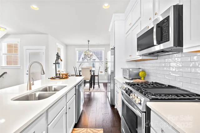 a kitchen with stainless steel appliances granite countertop a stove a sink and a microwave