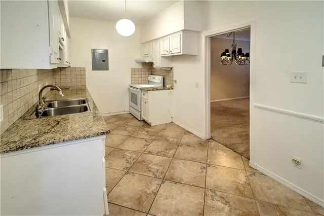 a kitchen with granite countertop a sink a stove and a refrigerator