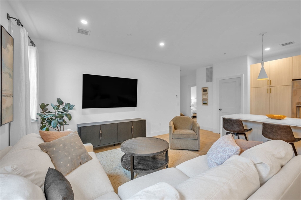 5245 Washington Street, Unit 5 Boston, MA 02132 - Photo 11 of 37 a living room with furniture and a flat screen tv