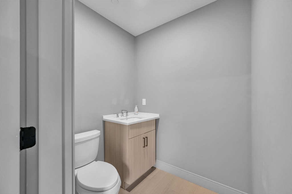 5245 Washington Street, Unit 5 Boston, MA 02132 - Photo 29 of 37 a bathroom with a toilet a sink and mirror