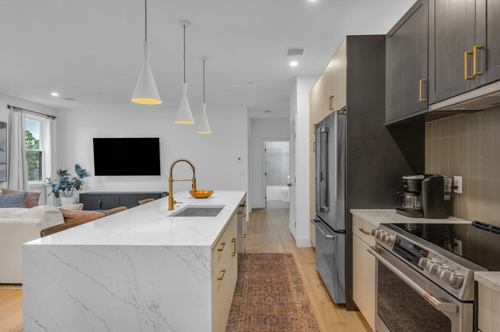 5245 Washington Street, Unit 5 Boston, MA 02132 - Photo 3 of 37 a kitchen with stainless steel appliances granite countertop a sink a stove and a refrigerator