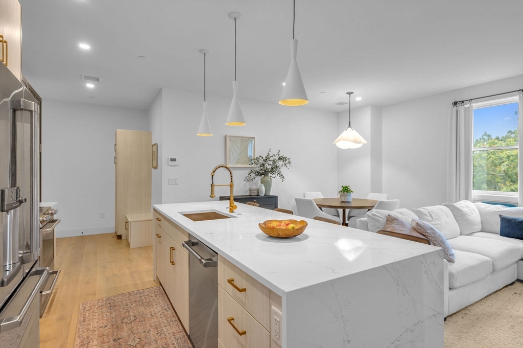 5245 Washington Street, Unit 5 Boston, MA 02132 - Photo 5 of 37 a kitchen with a sink a stove and chairs