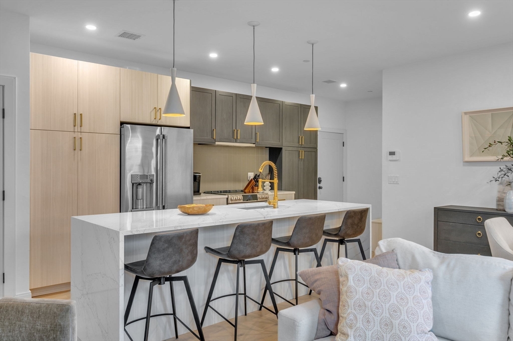 5245 Washington Street, Unit 5 Boston, MA 02132 - Photo 10 of 37 a kitchen with stainless steel appliances kitchen island granite countertop a dining table and chairs