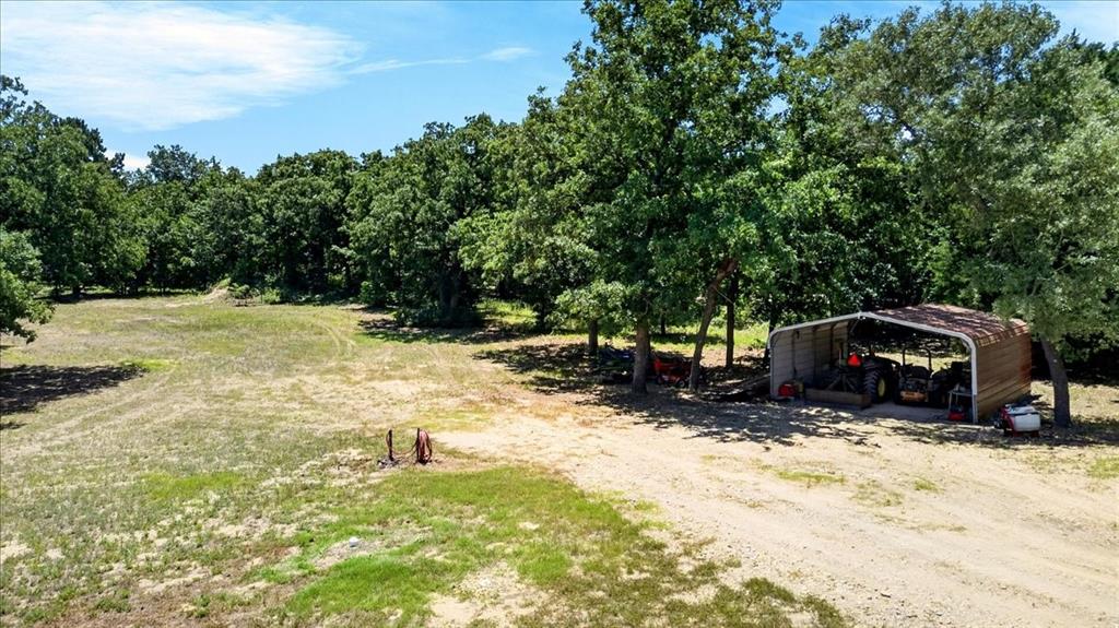 11591 Farm To Market 59 Athens, TX 75751 - Photo 32 of 40 Expansive clearing surrounded by mature trees, a gravel driveway, and a metal 2 car carport.