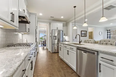 a large kitchen with stainless steel appliances granite countertop a sink a stove and a refrigerator