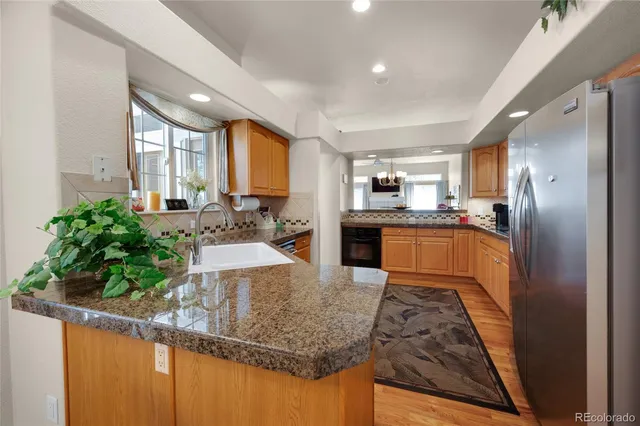 a kitchen with stainless steel appliances granite countertop sink stove refrigerator and cabinets