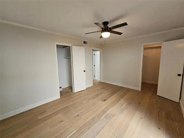 a view of empty room with wooden floor and fan