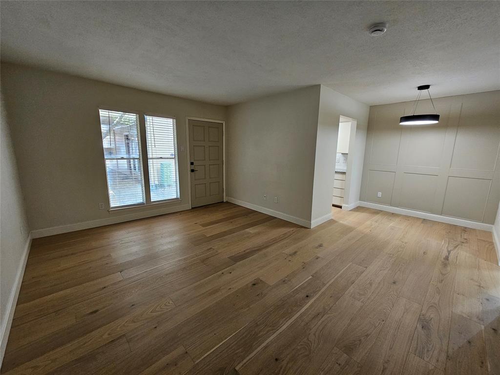 4327 Holland Avenue, Unit 102 Dallas, TX 75219 - Photo 10 of 20 an empty room with wooden floor and windows